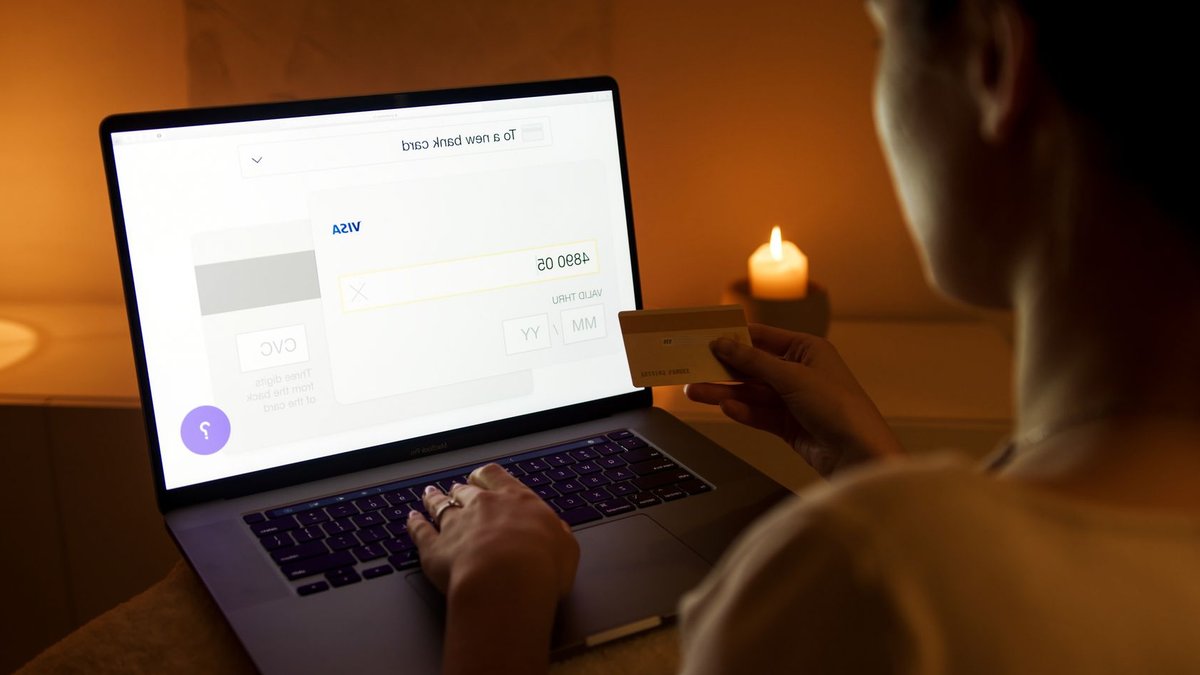 A woman makes a secure online payment using a laptop and credit card in a cozy setting.
