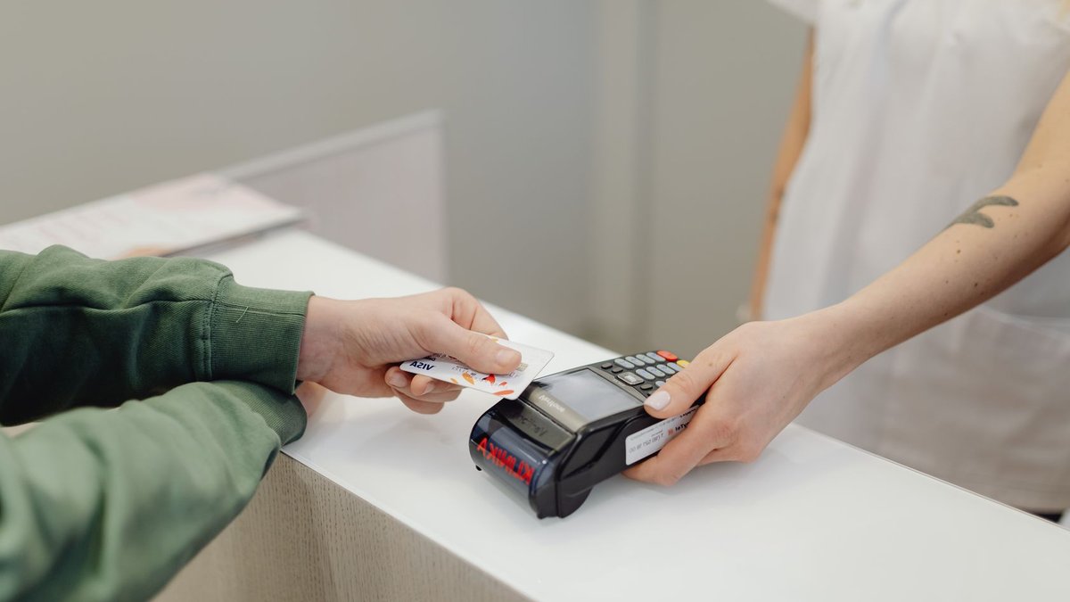 Morrisons boosts loyalty app with tailored deals and shopping tools Person using a bank card for contactless payment at a modern checkout counter.