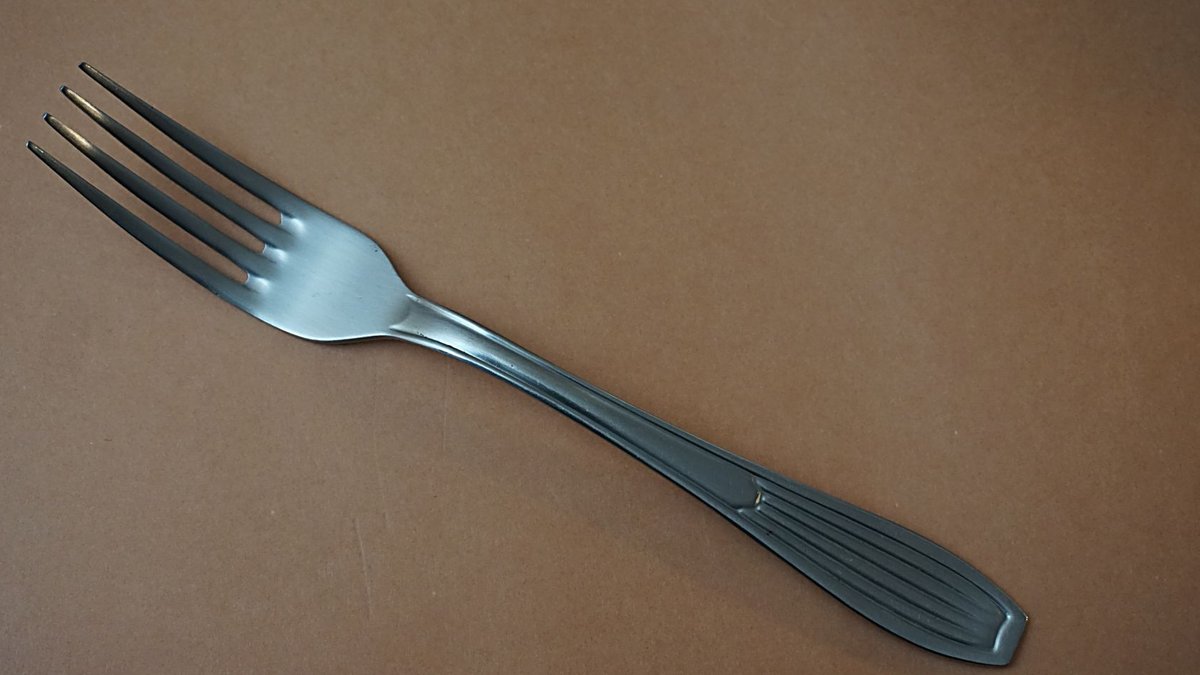 A simple yet elegant stainless steel fork placed on a brown surface.