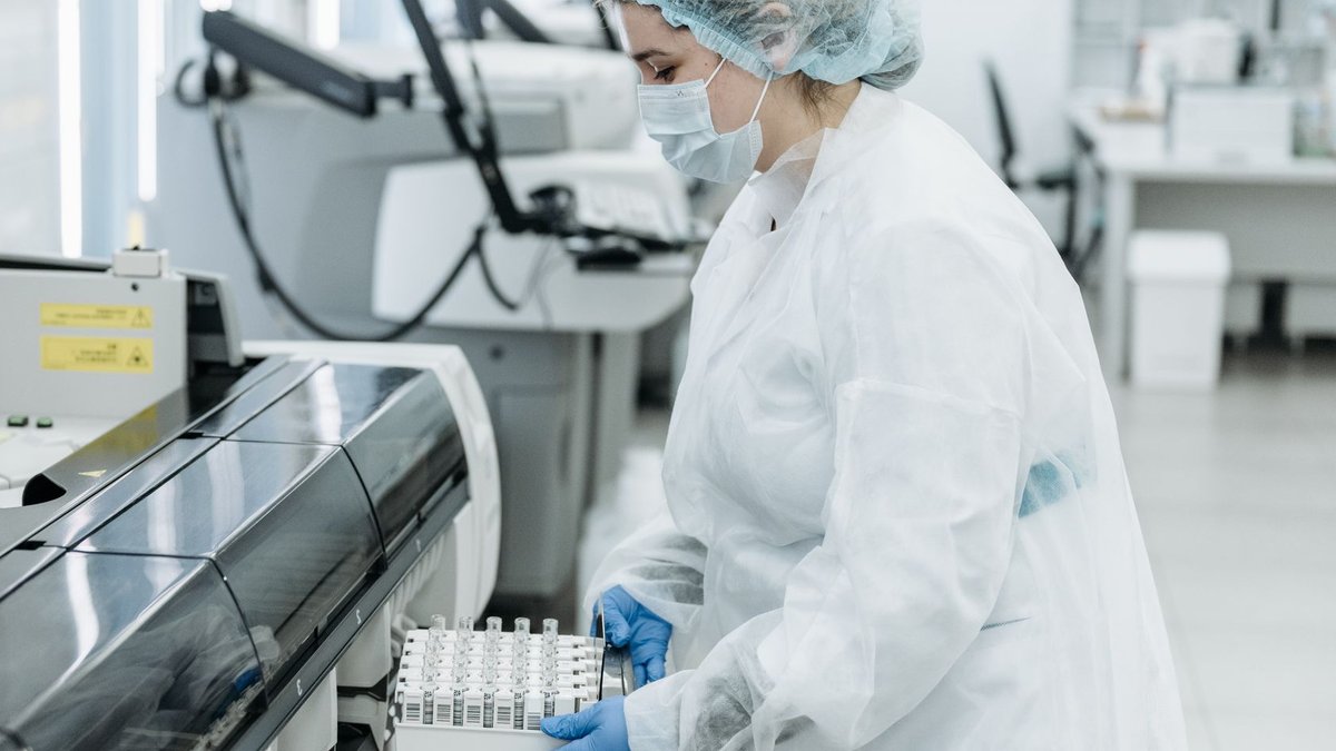 Laboratory scientist in protective gear working with medical samples.