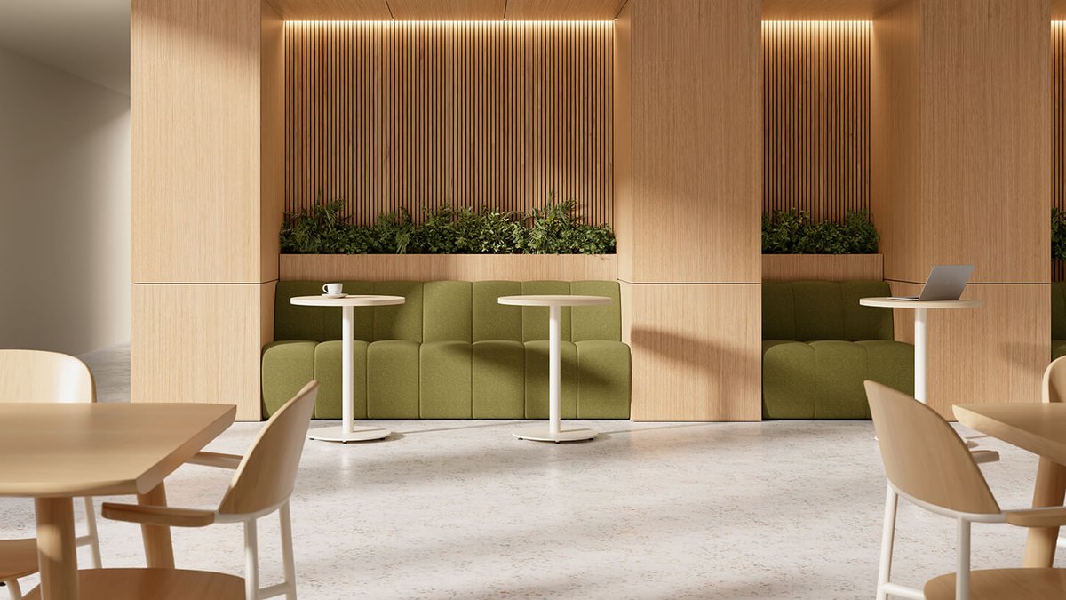 Modern café interior with light wood furniture, green cushioned seating, Keilhauer modular seating, white tables, plants, and