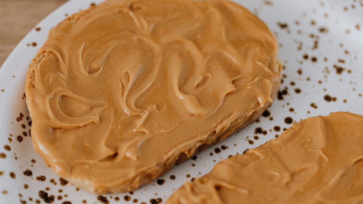 Creamy peanut butter spread on toast on a speckled plate, delicious breakfast idea.