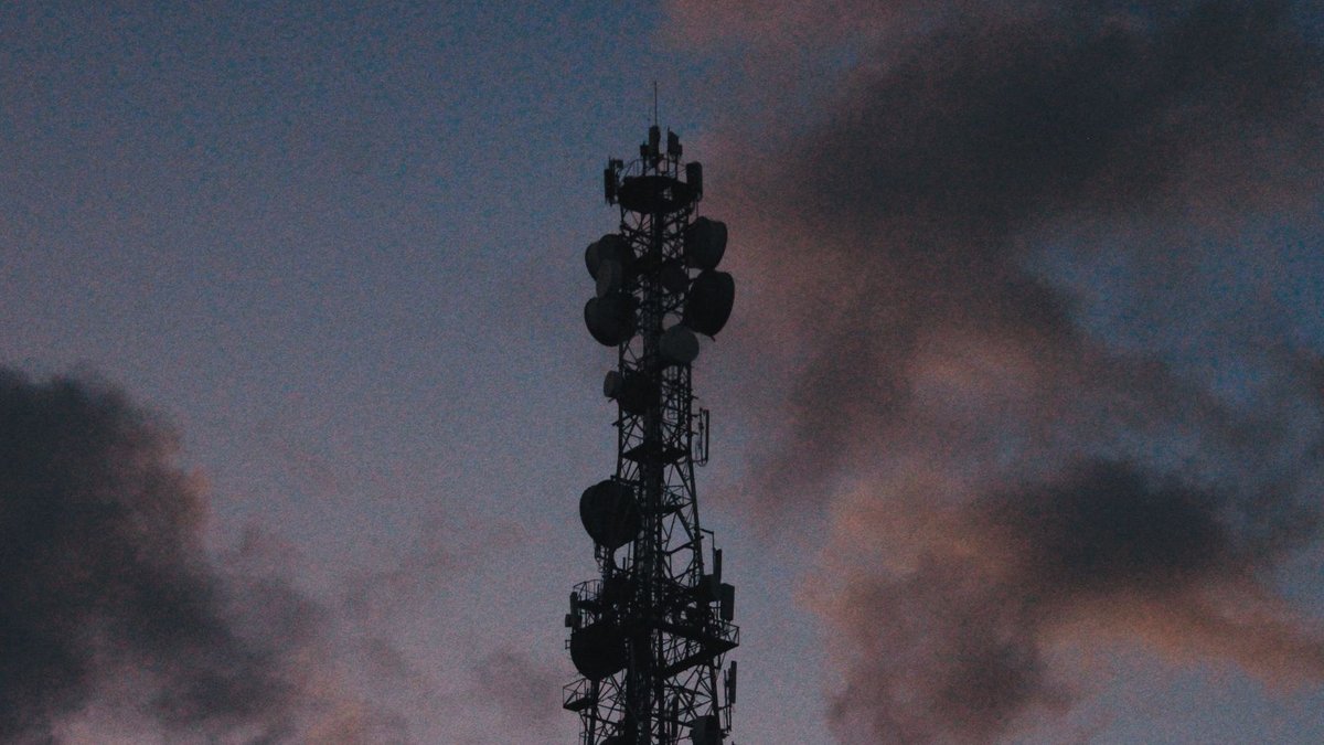 Nigeria struggles with slow 5G adoption despite 4G dominance Silhouette of a telecommunications tower against a vibrant twilight sky with clouds.