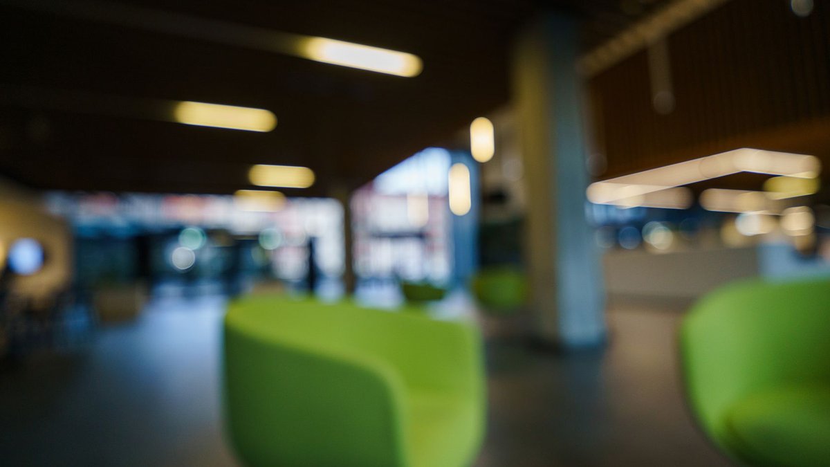 Contemporary office lobby with green chairs and blurred lighting, creating a modern and abstract look.