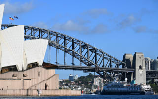 The expedition cruise ship Douglas Mawson dwarfed by the iconic Sydney Harbour Bridge and Sydney