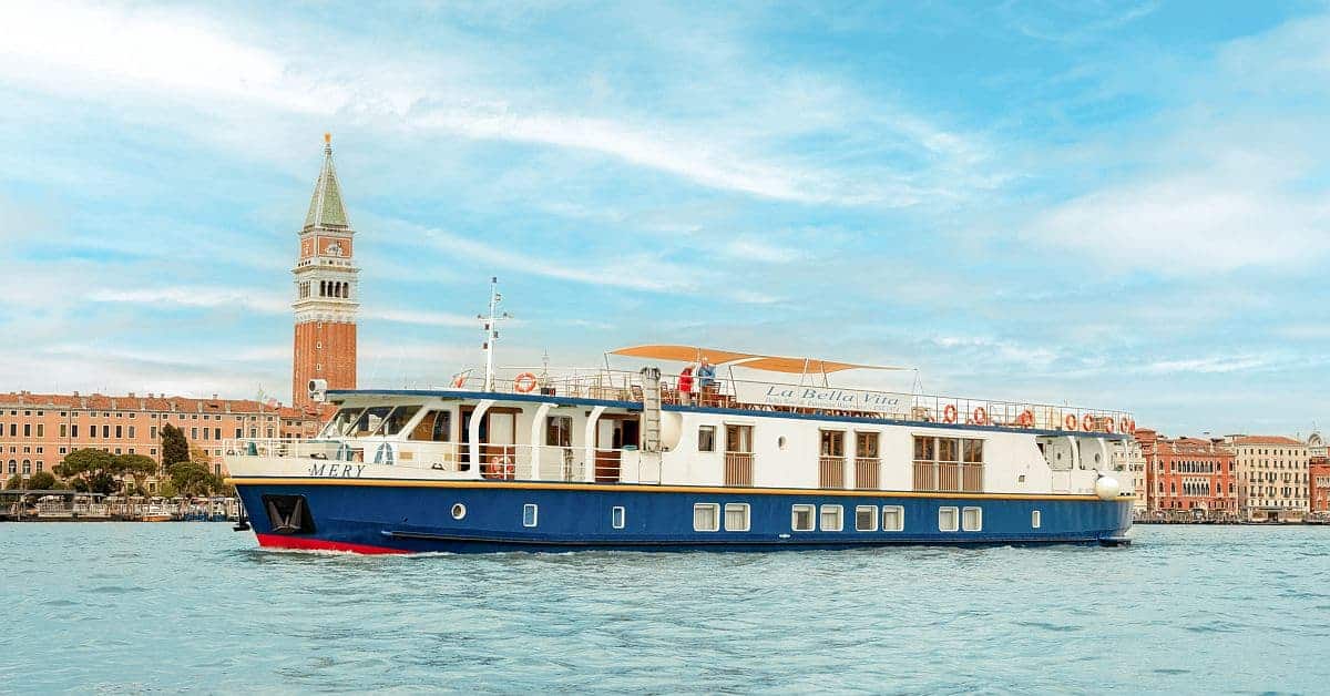 A modern luxury river cruise vessel named 'Mery' navigates the turquoise waters of the Grand Canal
