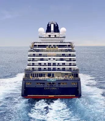 A full rear view of the Explora I luxury cruise ship traveling through open ocean, showcasing its