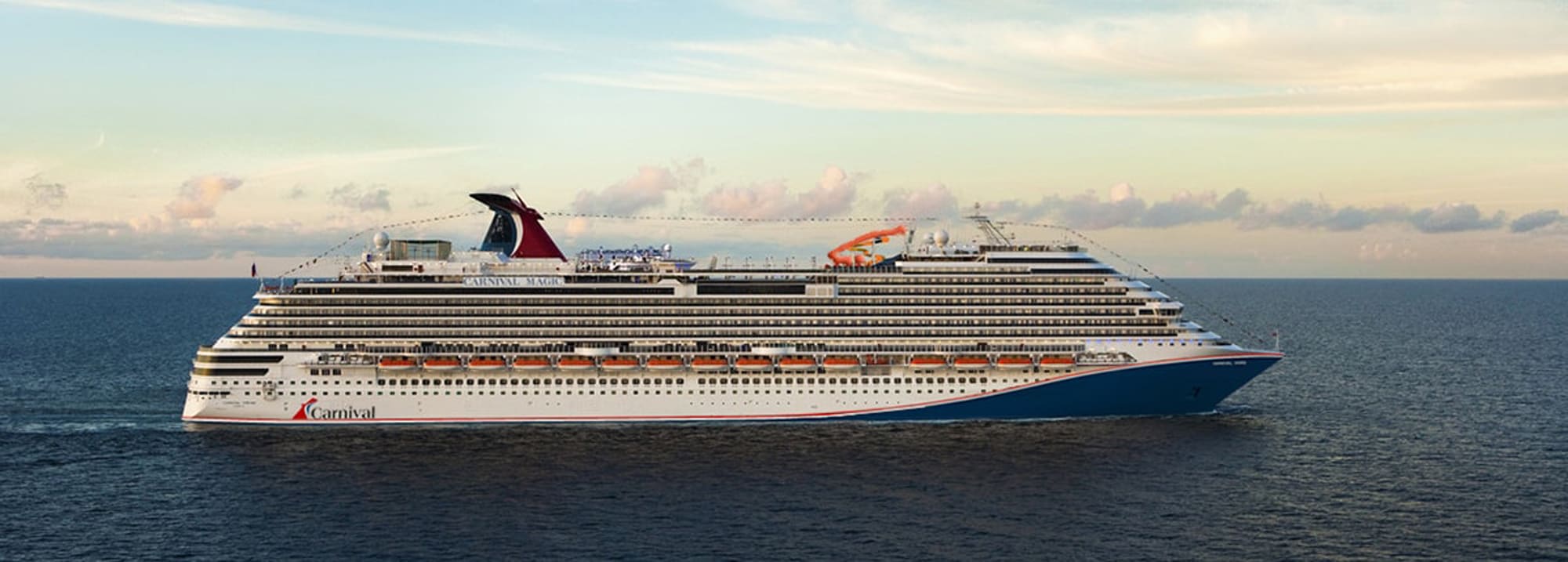 A large Carnival cruise ship sailing across a calm blue sea under a soft, cloudy sky during golden