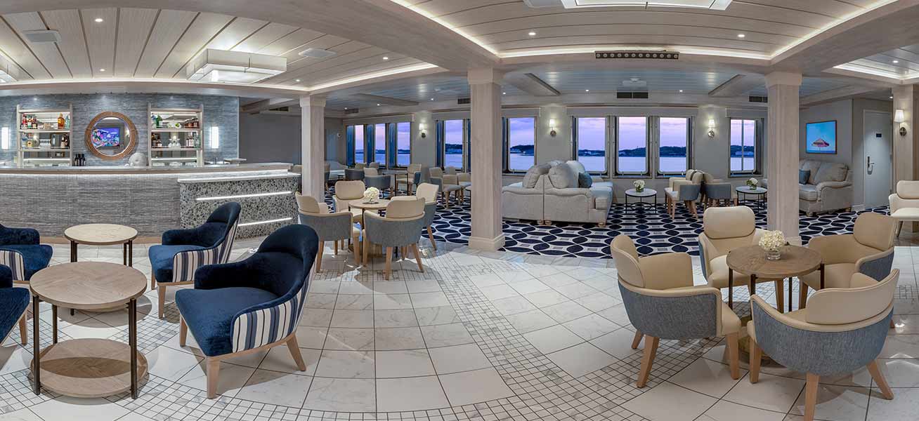 An elegant and spacious lounge area aboard a modern cruise ship featuring contemporary furnishings