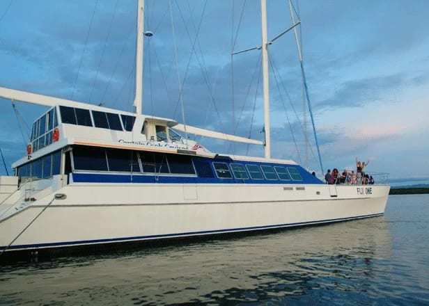A stunning white and blue gulet-style sailing yacht anchored in calm waters during golden hour
