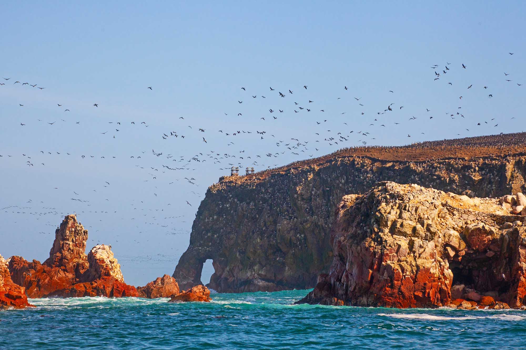 A stunning coastal seascape featuring towering red and golden rock formations with a distinctive