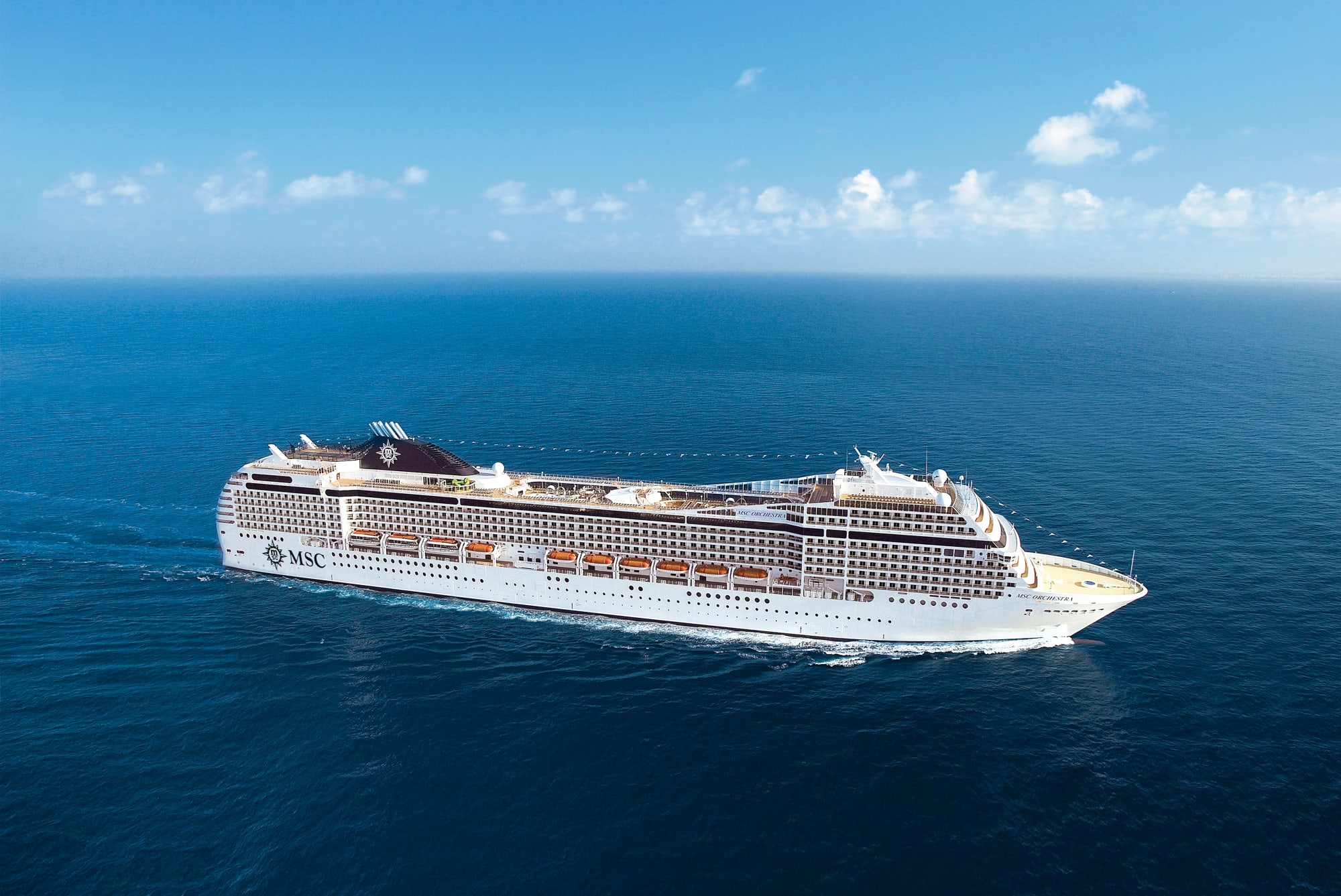 A large modern cruise ship operated by MSC Cruises, captured sailing on open ocean under clear blue