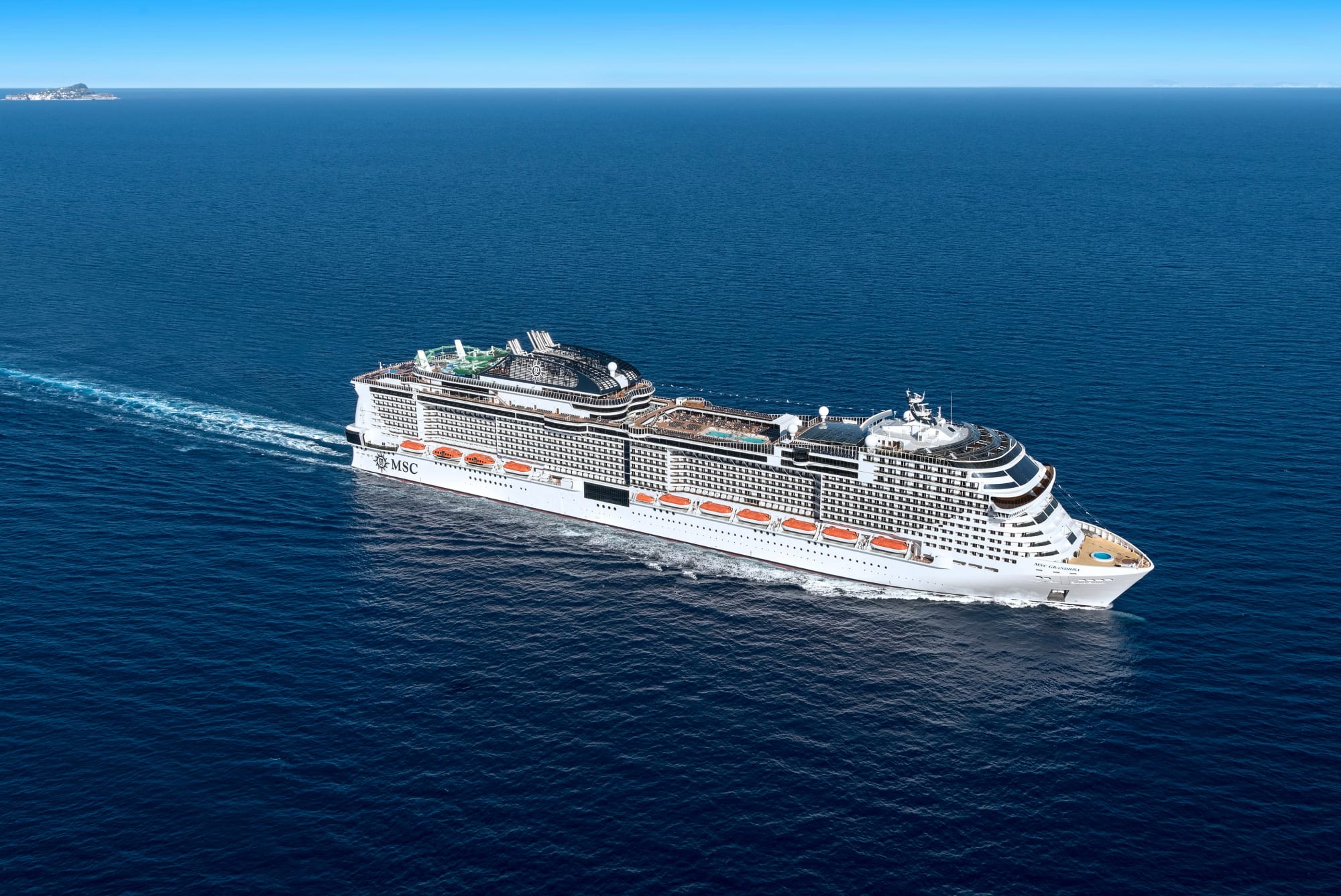 A modern mega-ship cruise vessel from MSC Cruises sailing through open ocean waters. The large