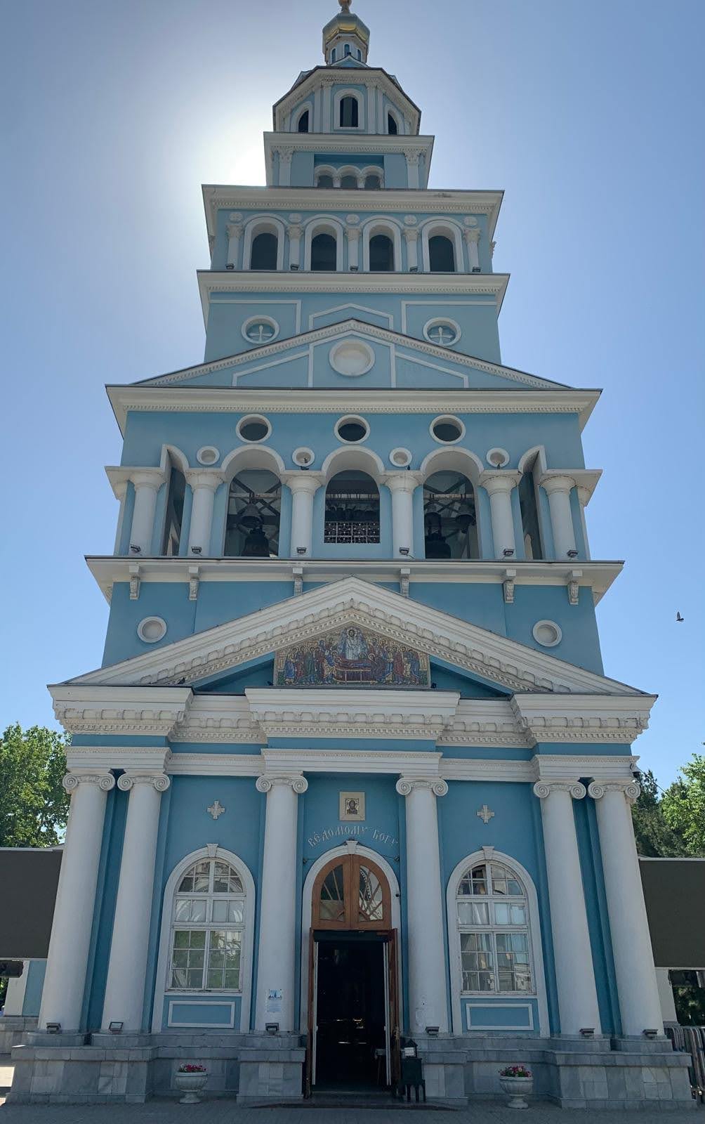 A striking neoclassical church featuring a distinctive light blue façade with white Corinthian