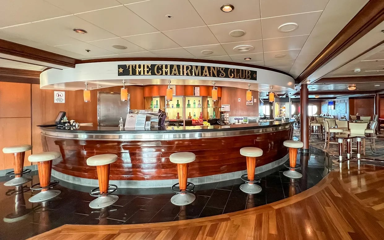 An elegant curved bar lounge aboard the Cordelia cruise ship, featuring a distinctive mahogany
