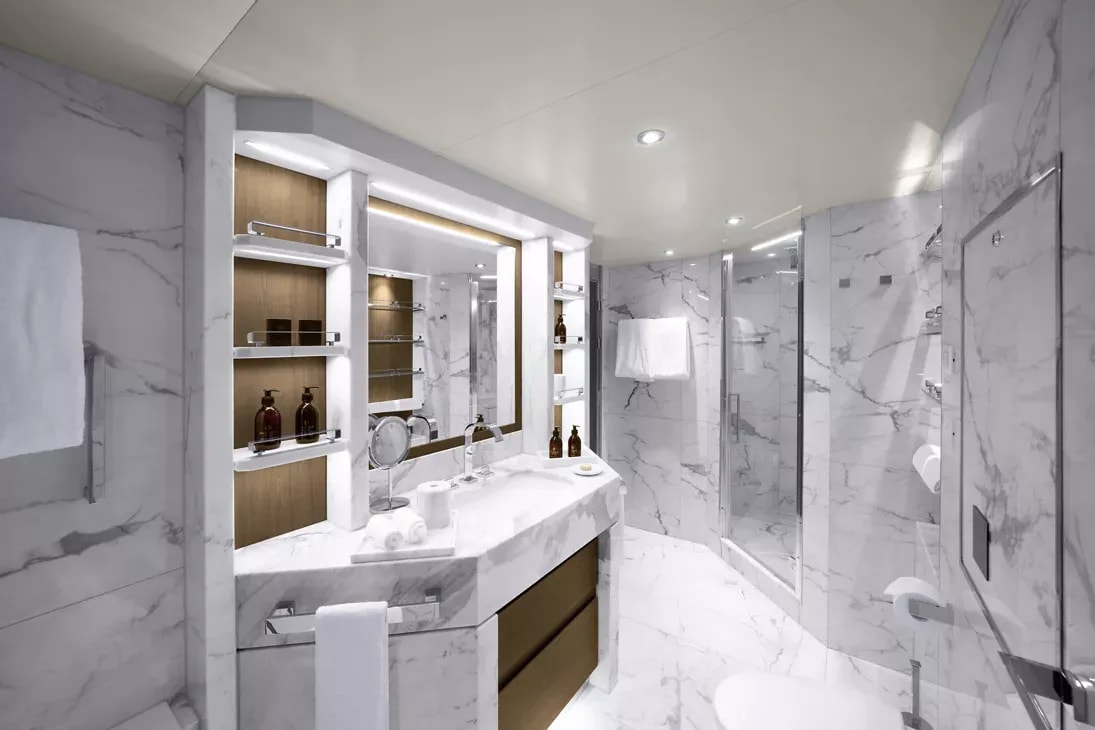 A contemporary luxury bathroom featuring white marble surfaces with gray veining, a double vanity