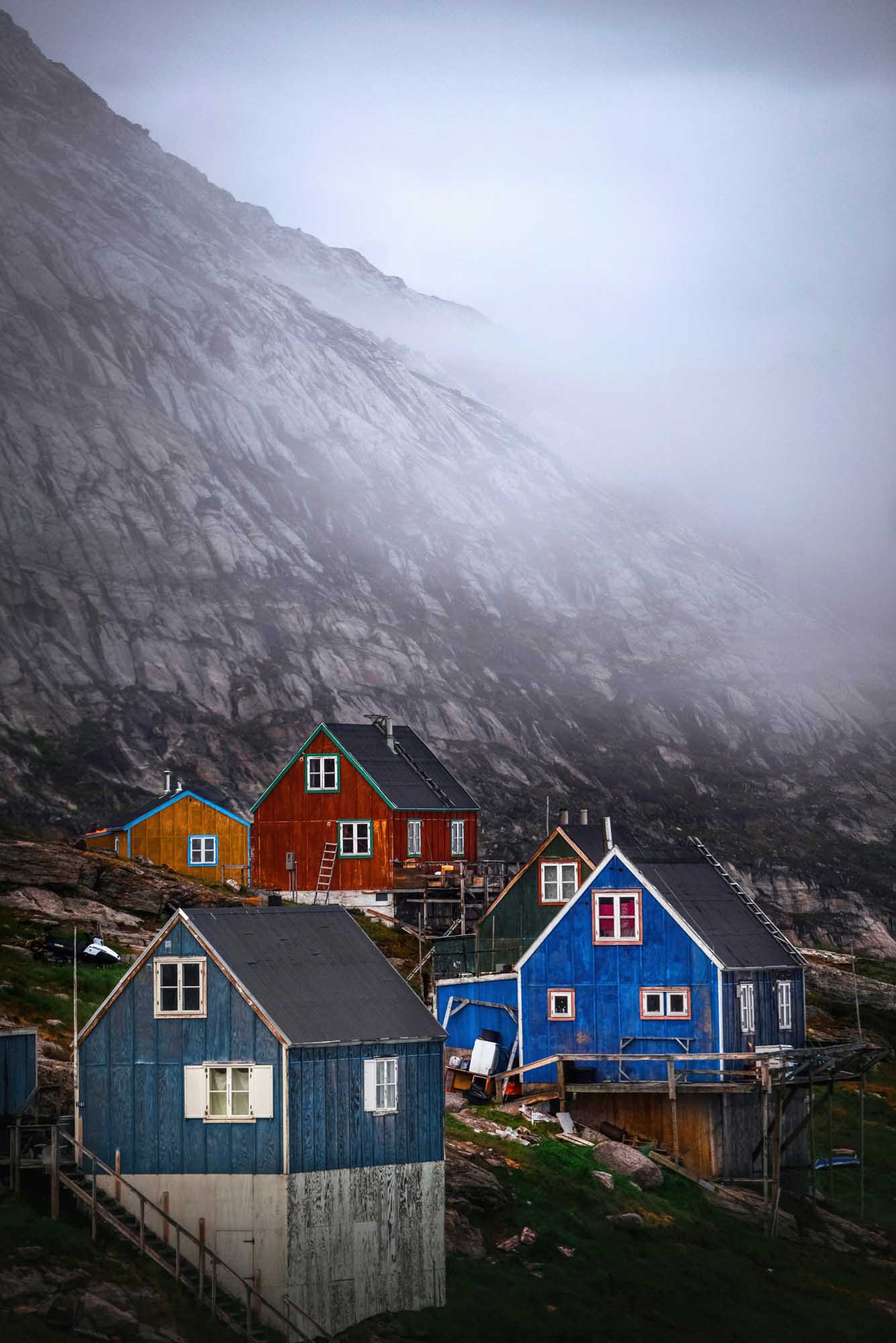 A picturesque collection of brightly colored traditional houses nestled at the base of a towering