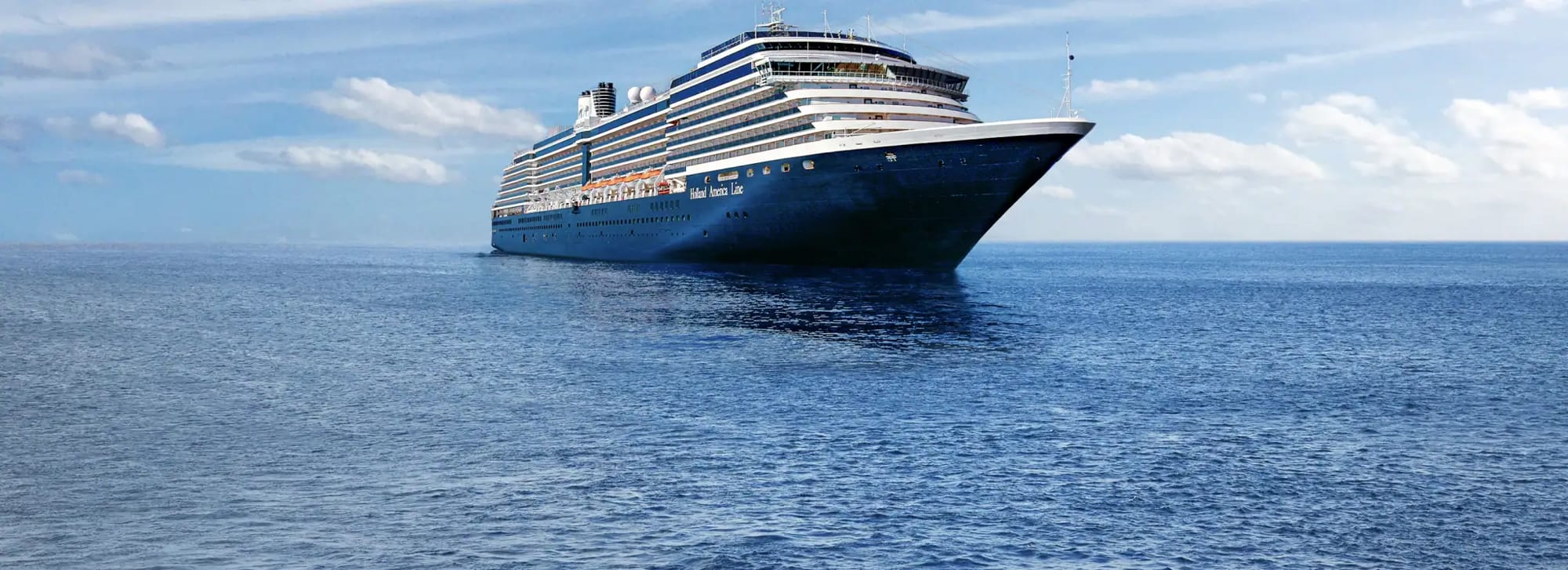 A large, elegant blue cruise ship sailing smoothly across a calm, expansive blue ocean under