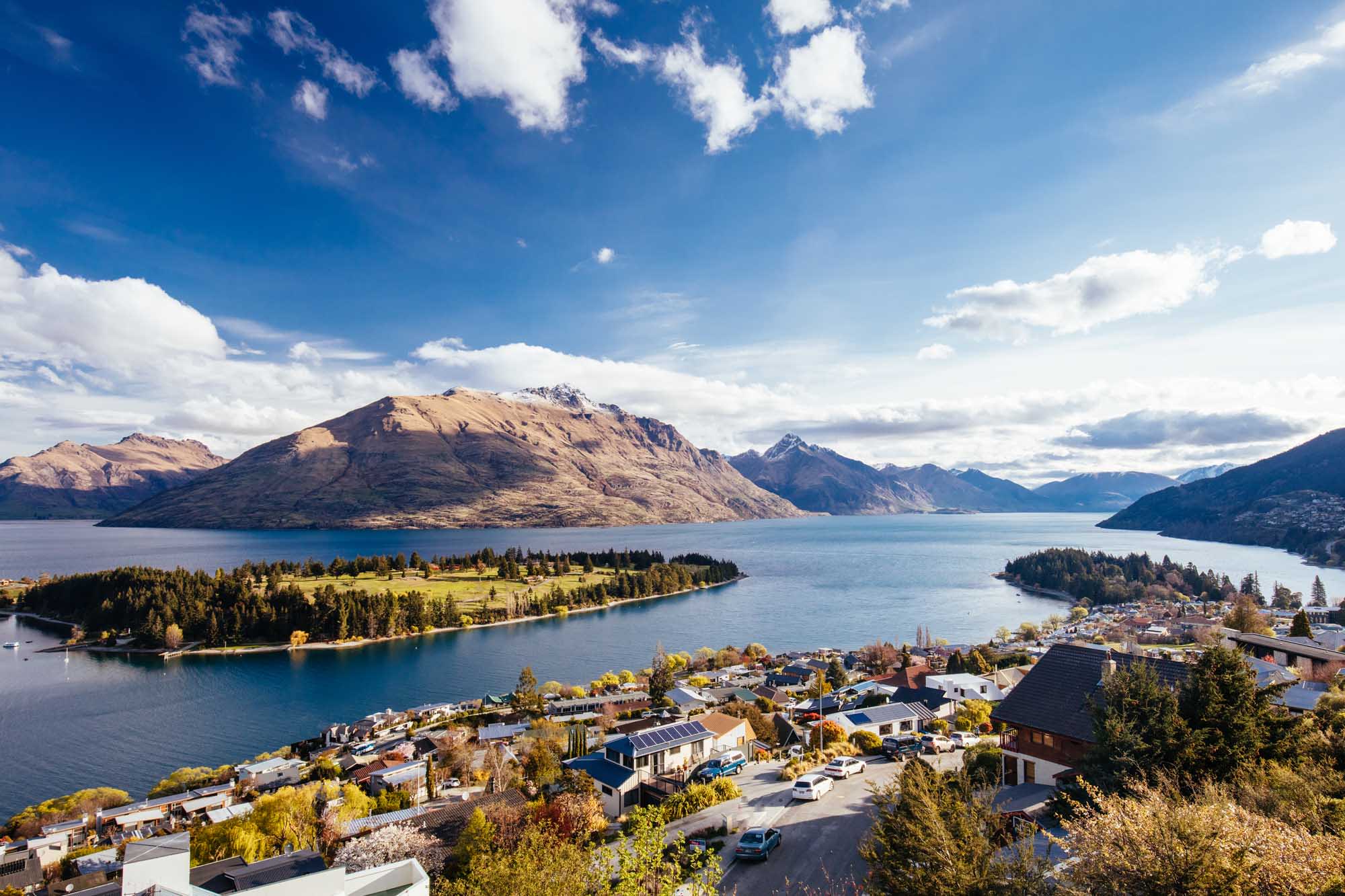 An aerial view of Queenstown, New Zealand, nestled on the shores of Lake Wakatipu with snow-capped