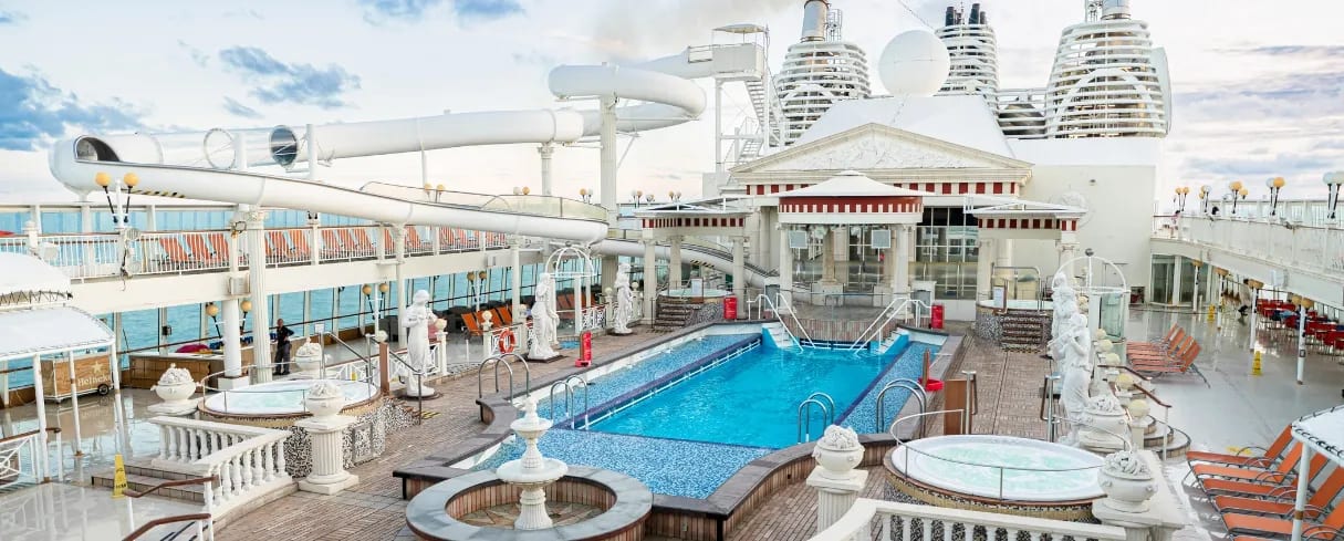 An expansive cruise ship pool deck featuring a grand Parthenon-themed architectural structure