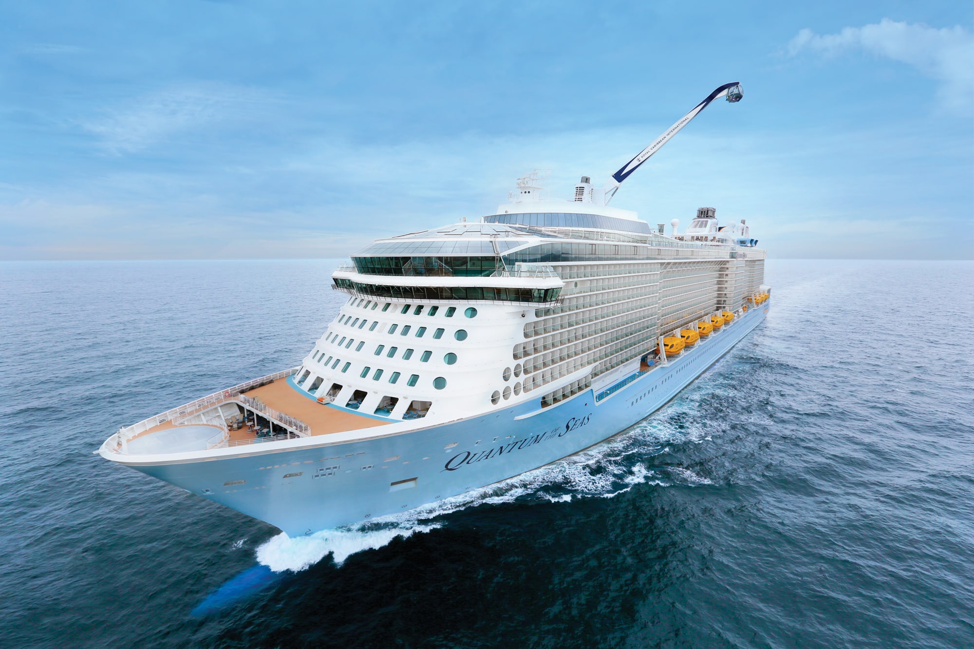 A large modern cruise ship photographed from above, sailing through calm blue ocean waters under