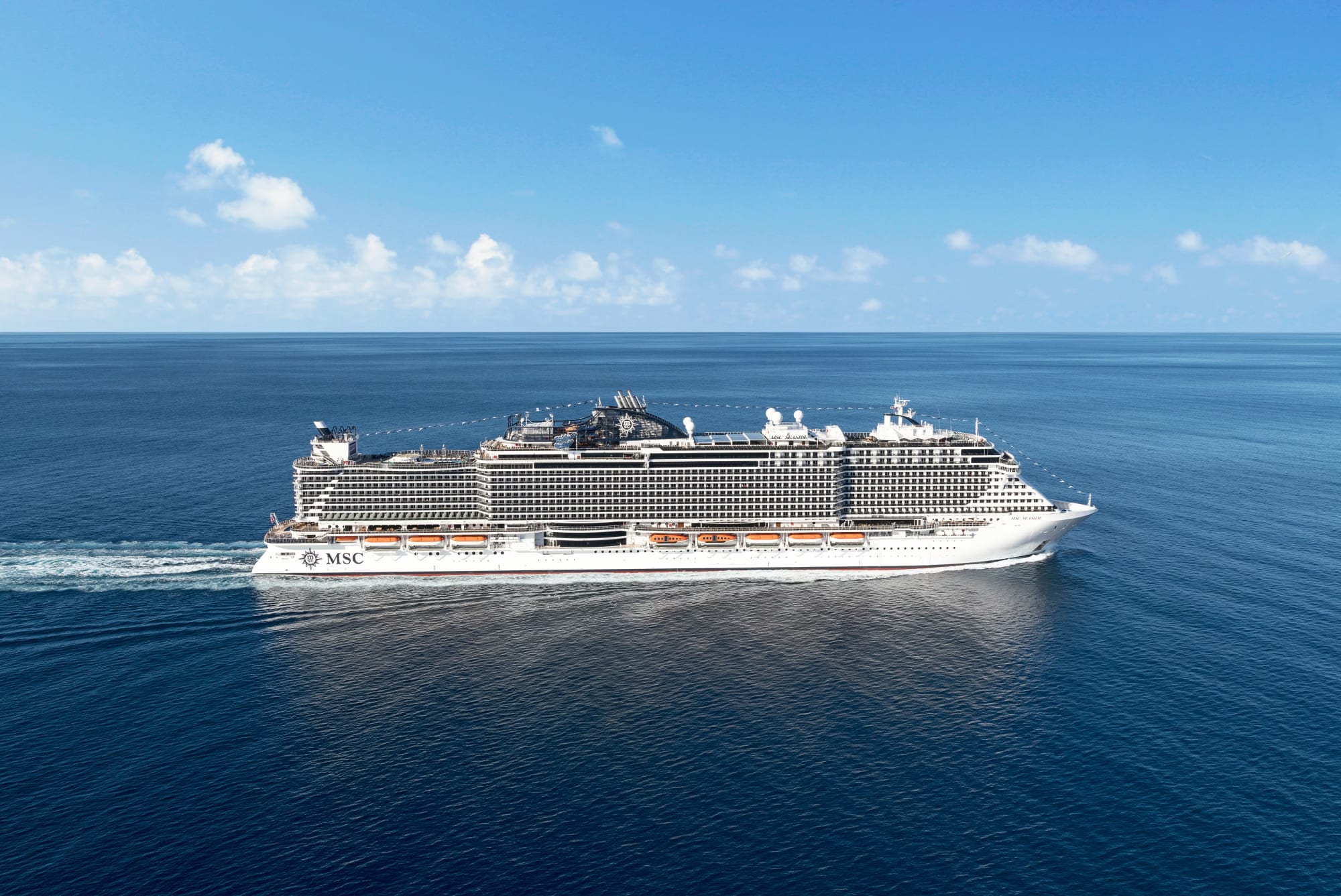 A large modern cruise ship operated by MSC Cruises sailing through calm blue ocean waters under