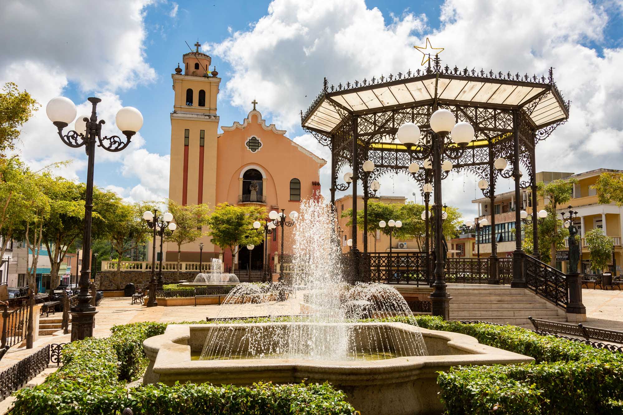A picturesque colonial-style town square in Barranquitas, Puerto Rico, featuring an ornate orange