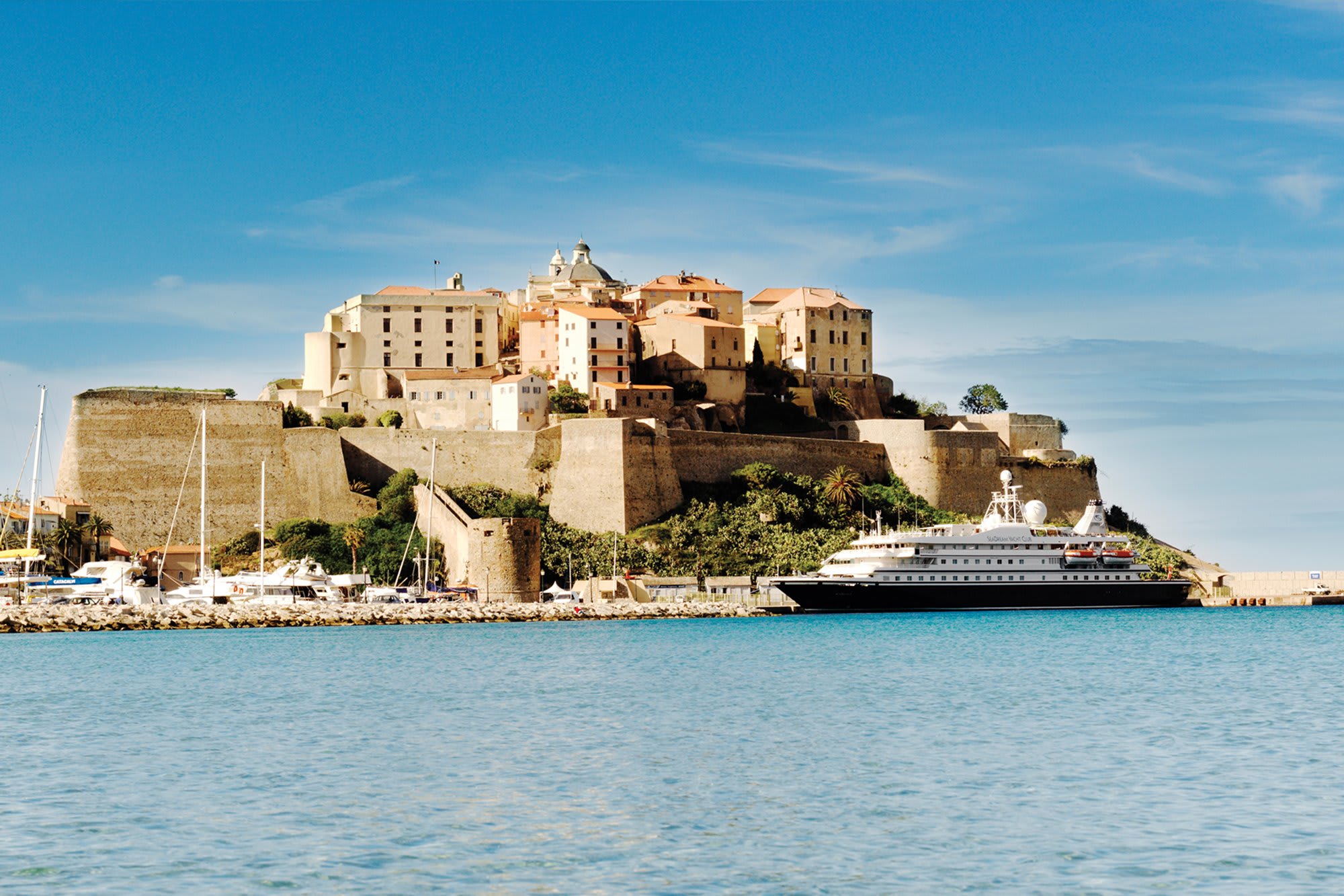 A luxury cruise ship docked at the historic port of Bonifacio, Corsica, with the impressive