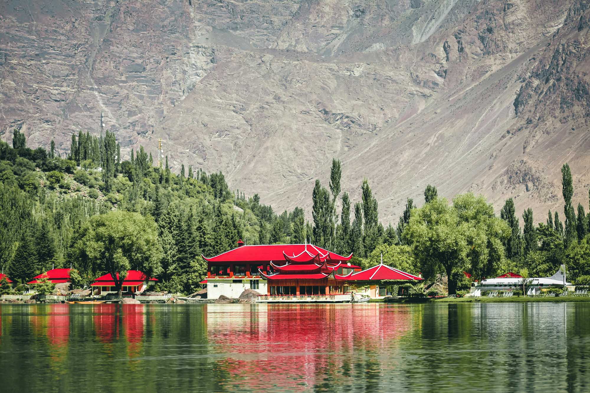 A striking traditional Asian temple with distinctive red tiered roofs is reflected in the calm