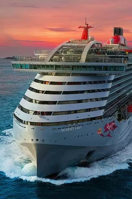 The Virgin Voyages cruise ship Scarlet Lady is captured at sea during golden hour, with