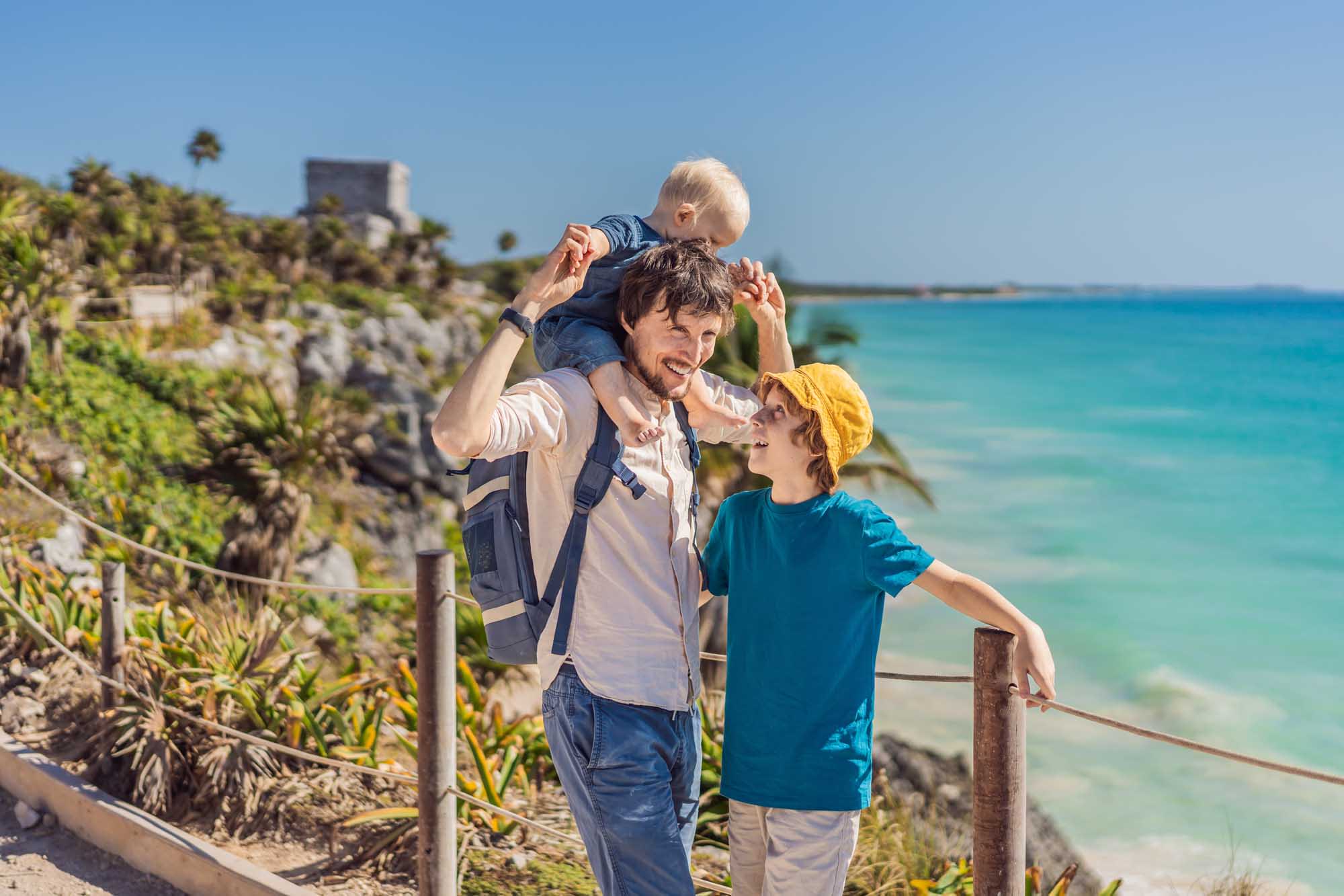 A father with two young sons enjoys a scenic moment at the clifftop Pre-Columbian Mayan walled city
