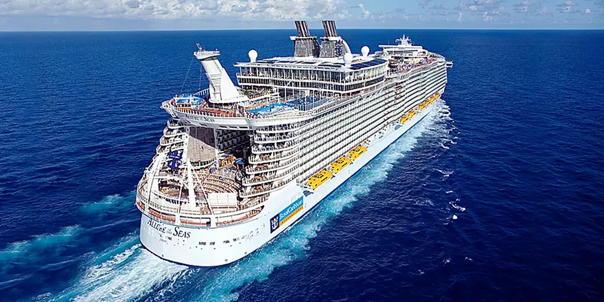 An aerial photograph of the Allure of the Seas, a massive modern cruise ship, sailing through clear