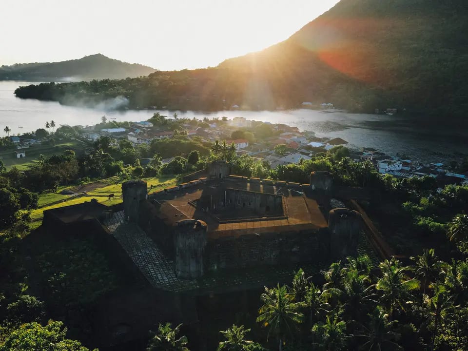 An aerial view of a weathered colonial-era fortification overlooking a lush tropical island
