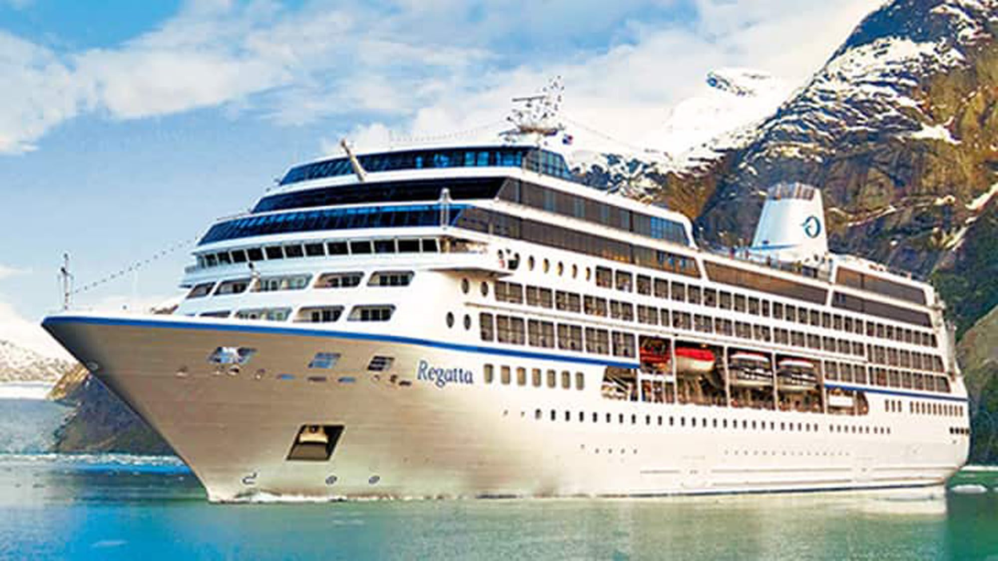 The Regatta, a luxury cruise ship with distinctive blue and white hull, is anchored in a pristine