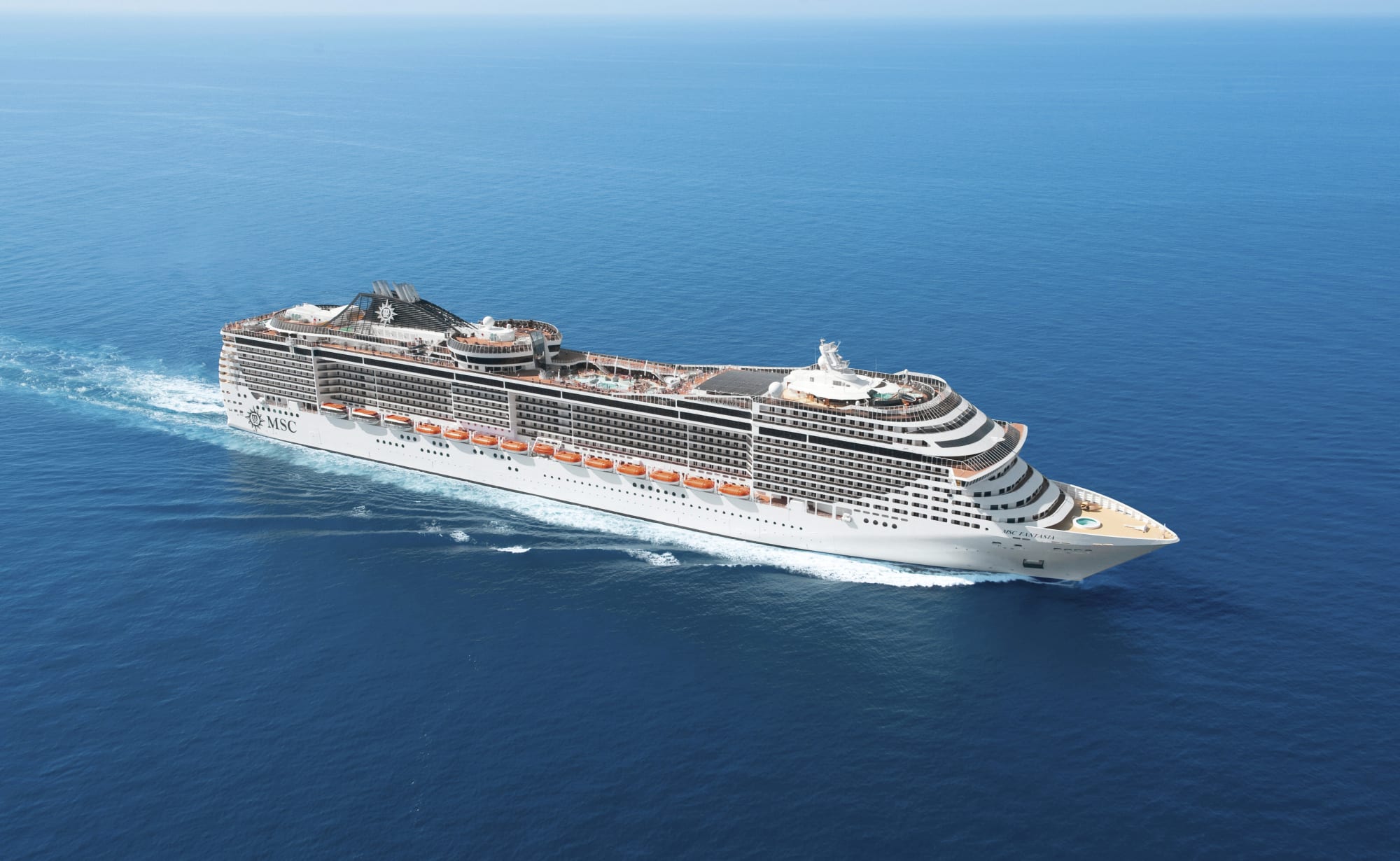 A modern large cruise ship with distinctive MSC branding visible on the hull, sailing through calm