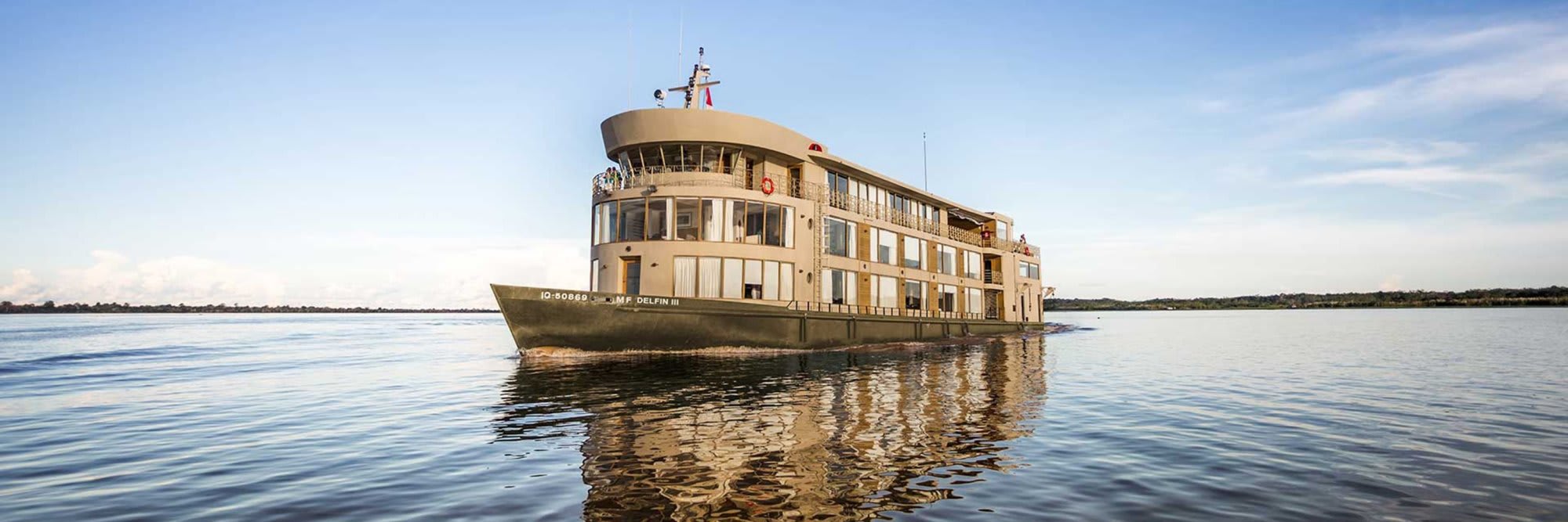 A multi-deck river cruise vessel operated by Avalon Waterways navigates through expansive, calm
