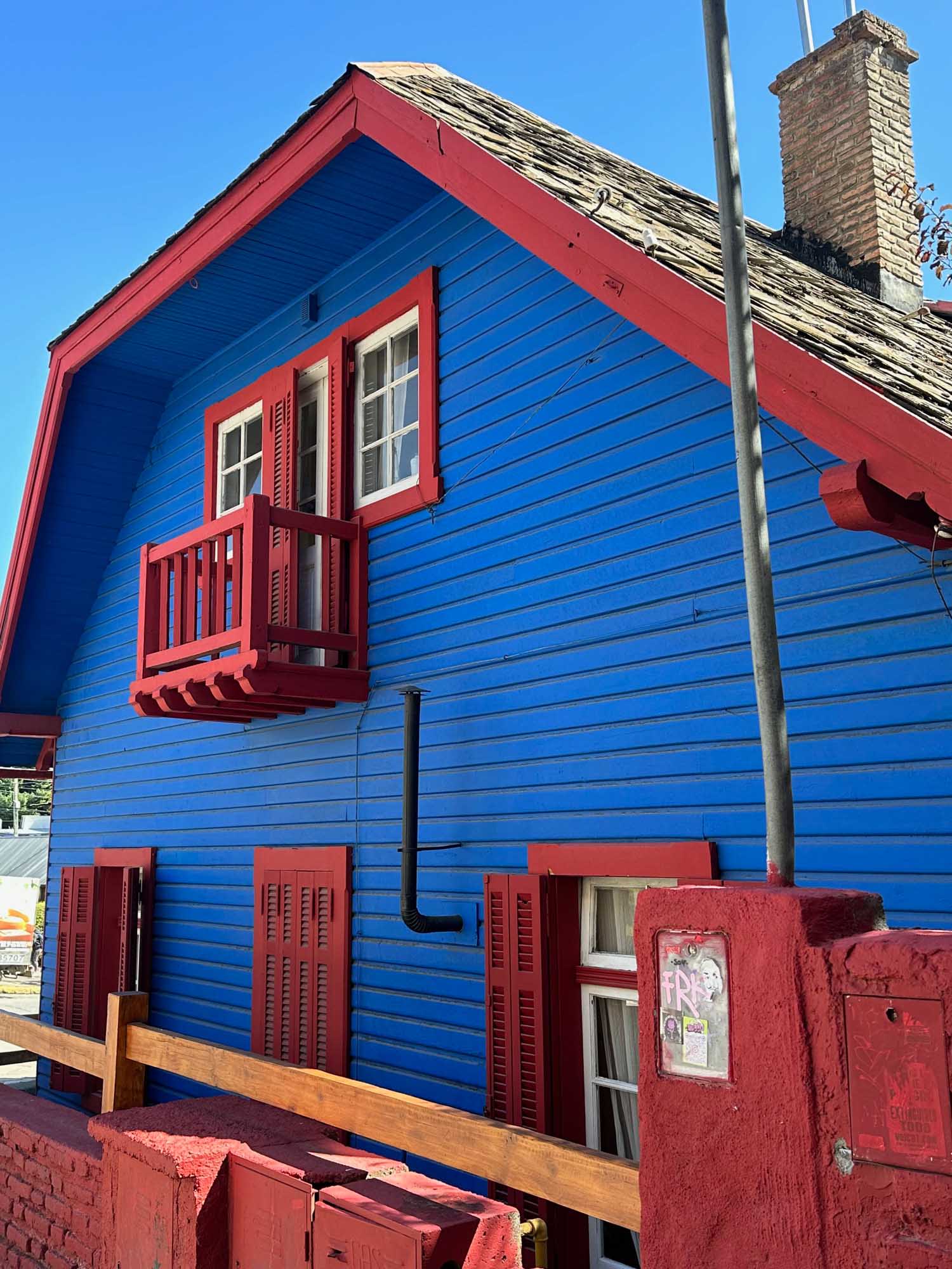 A striking residential building painted in bold blue with bright red trim and accents, featuring
