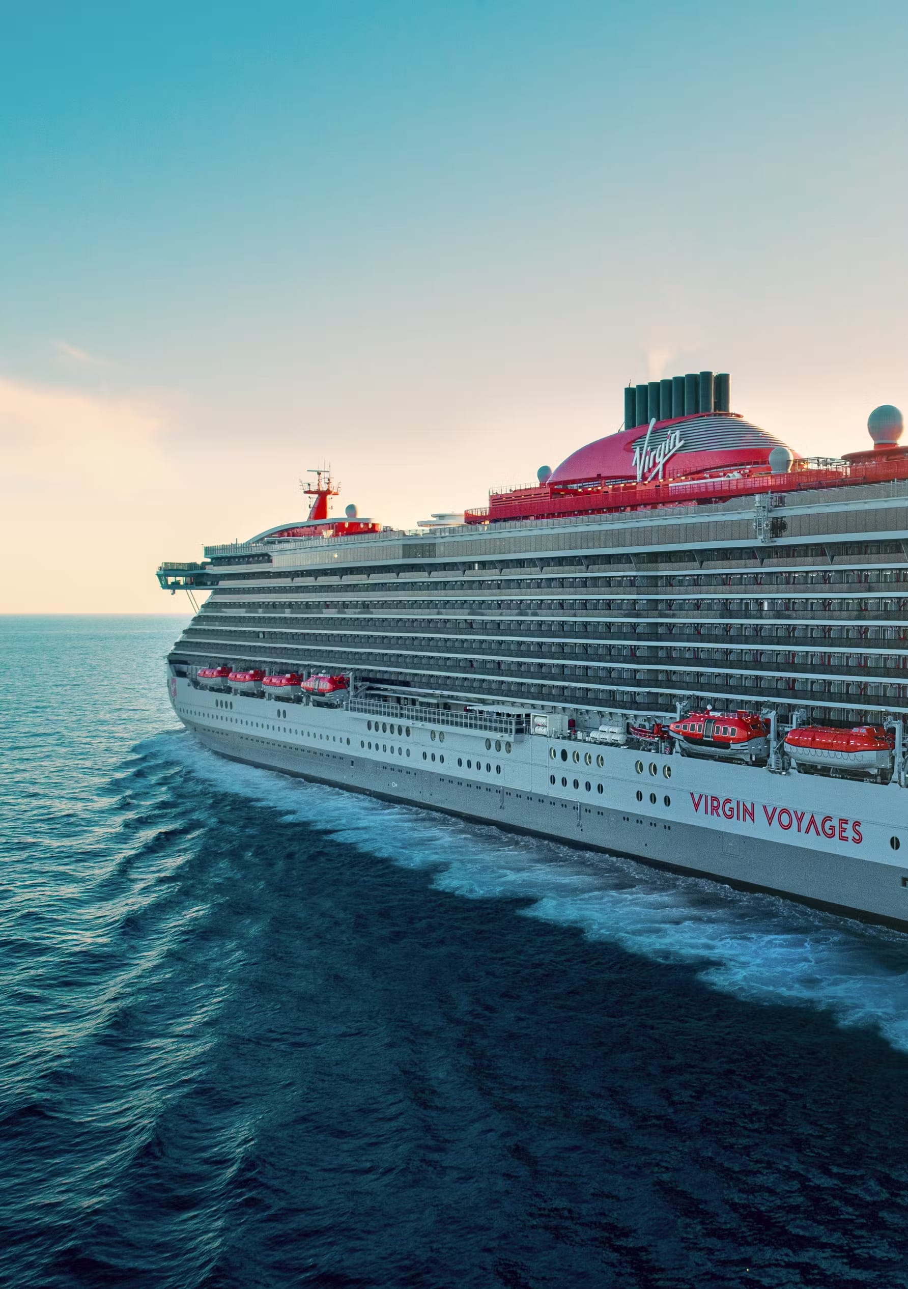 A stunning side profile of the Virgin Voyages Brilliant Lady cruise ship sailing on open turquoise