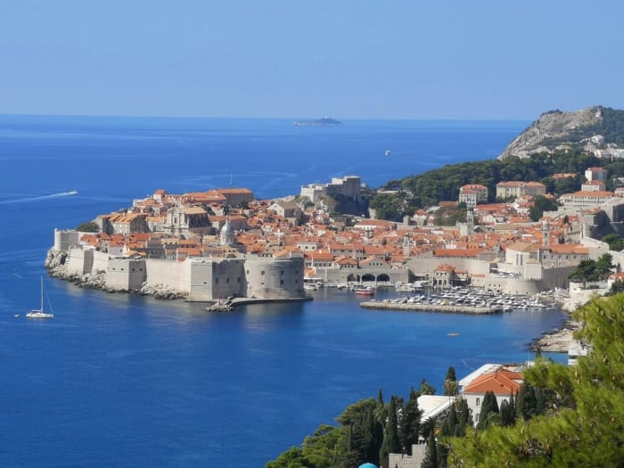 A stunning aerial photograph of Dubrovnik's iconic walled Old Town surrounded by brilliant