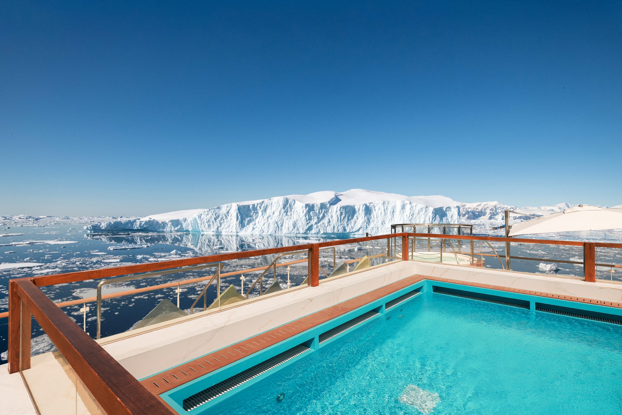 A stunning heated outdoor pool on an expedition cruise ship offers panoramic views of a massive