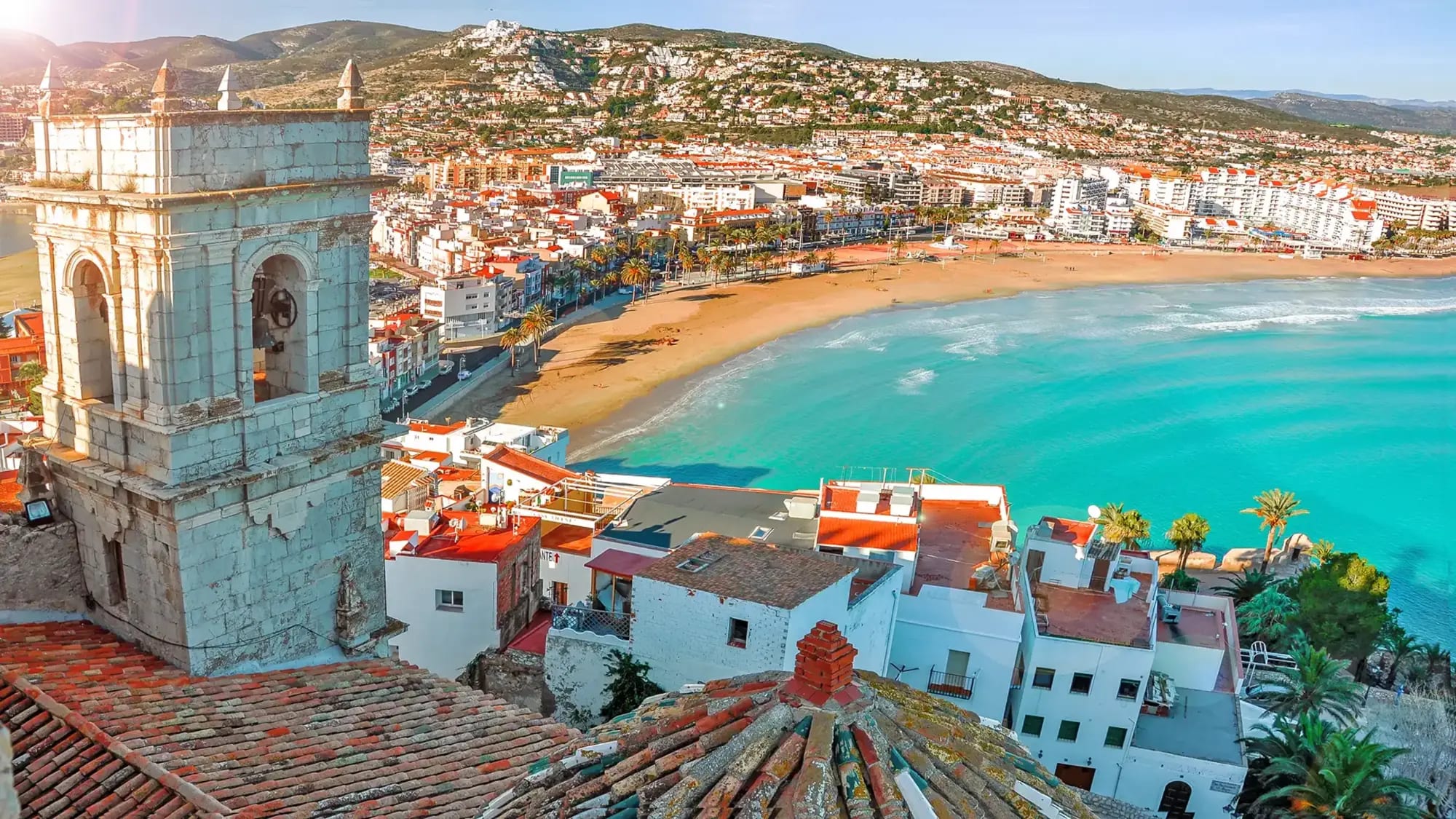 A picturesque Mediterranean coastal town featuring a distinctive turquoise-tiled historic tower
