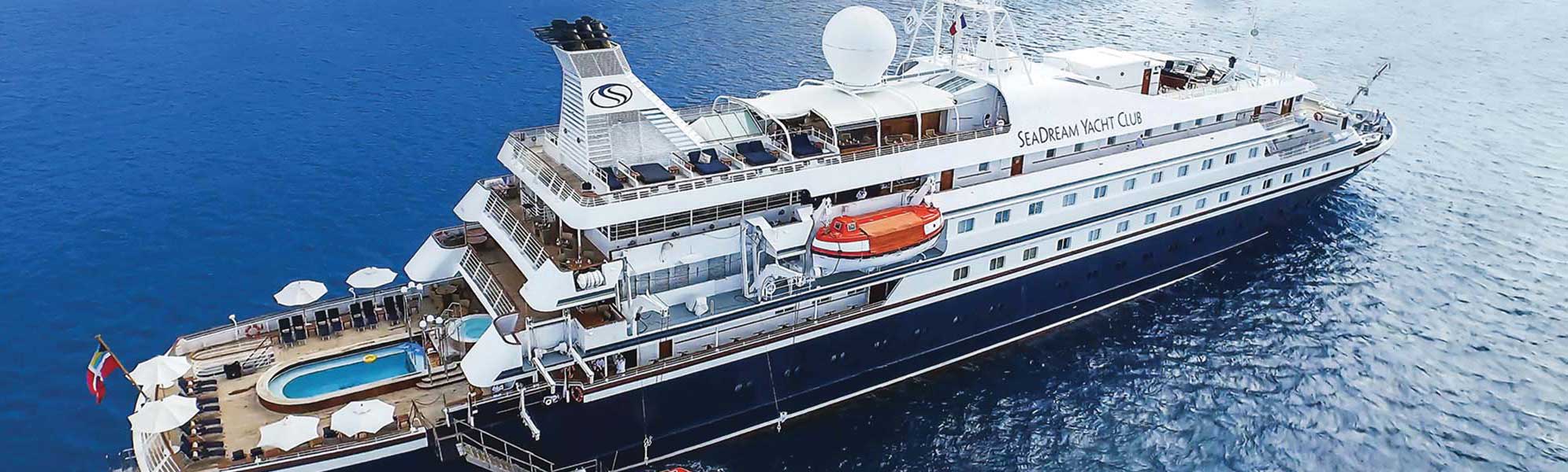 An aerial view of the SeaDream Yacht Club expedition cruise vessel anchored in clear blue waters