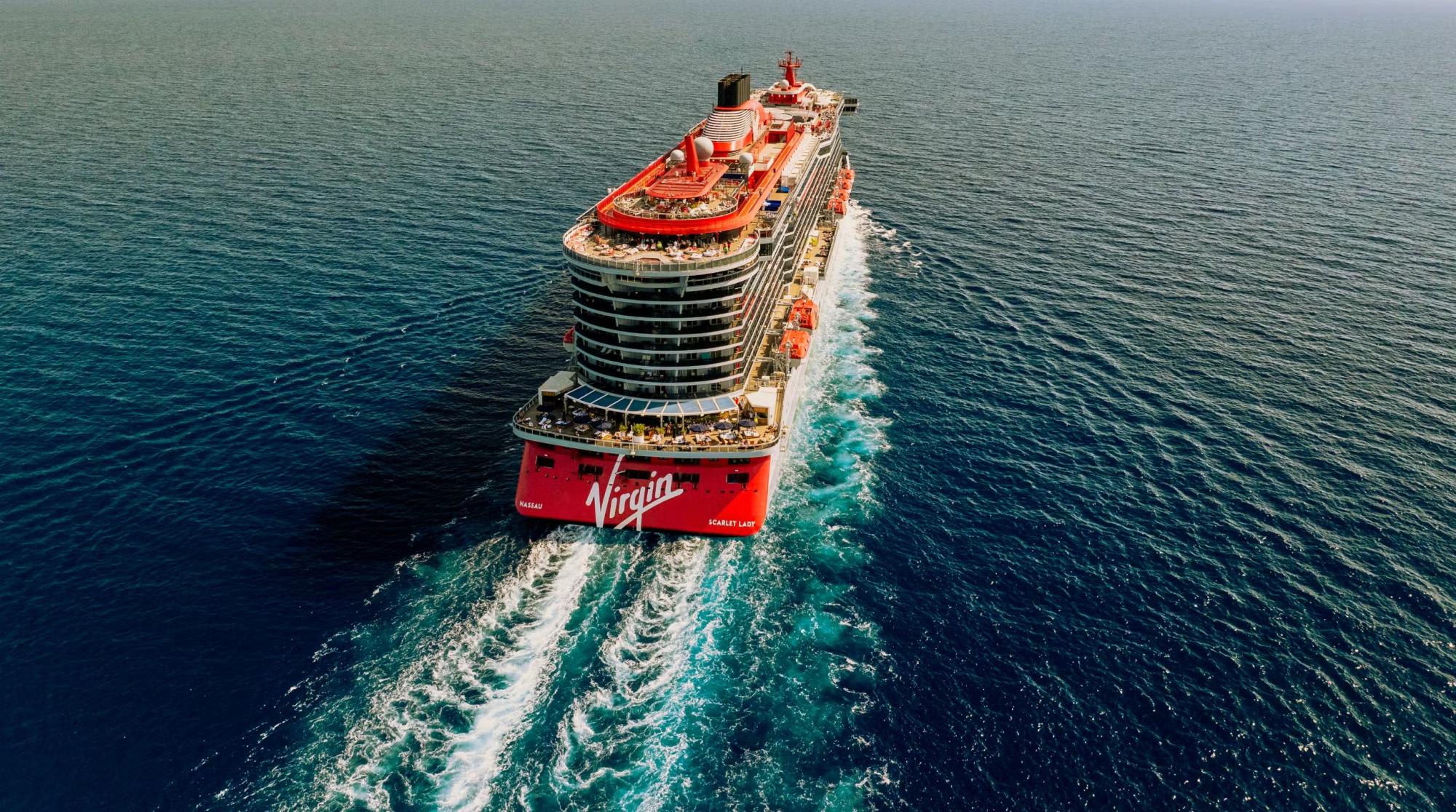 An aerial view of the Virgin Voyages Scarlet Lady cruise ship navigating open ocean waters