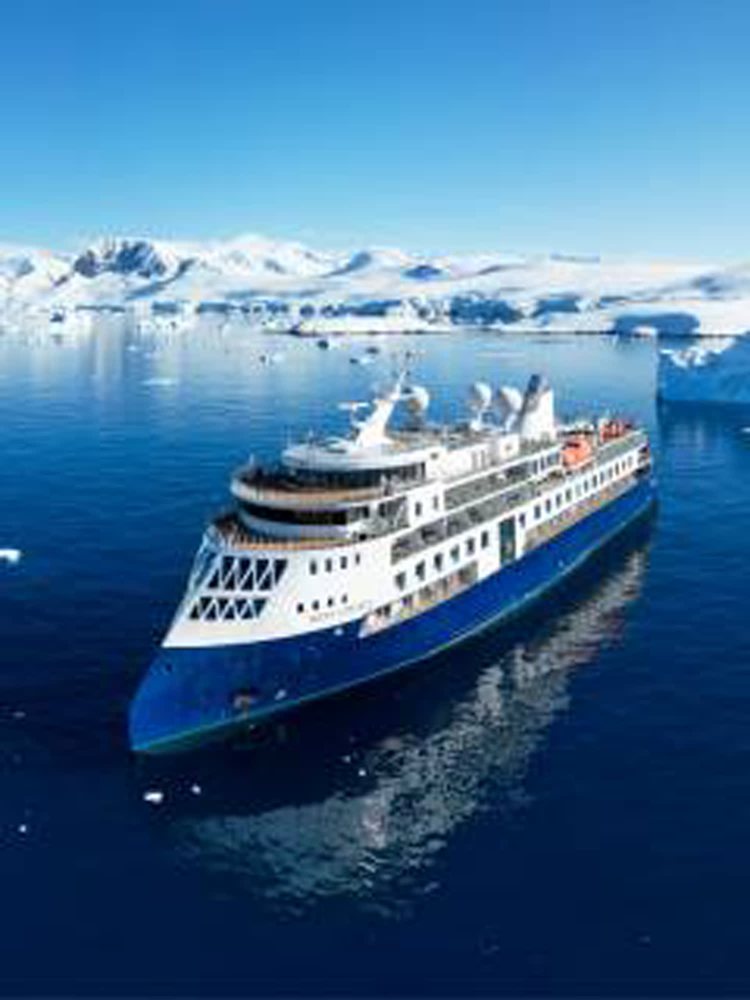 A modern expedition cruise ship sailing through a pristine polar seascape with snow-covered