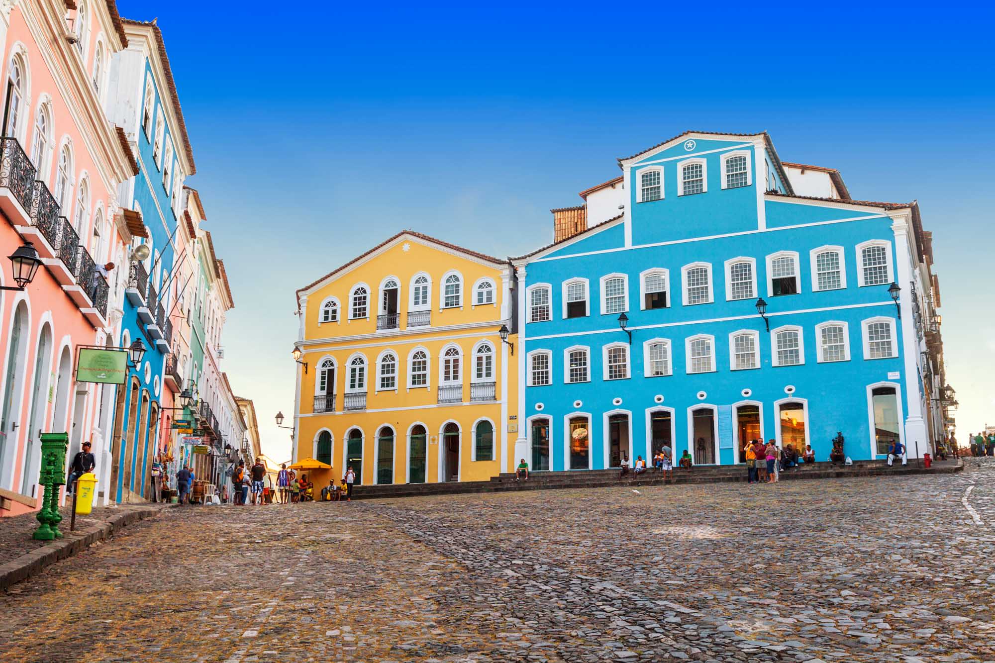 A vibrant historic plaza featuring beautifully preserved colonial buildings painted in striking