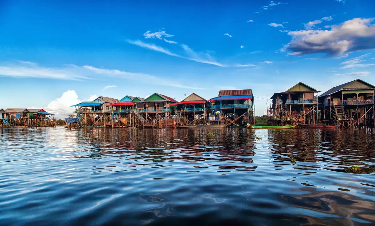 A vibrant floating village featuring traditional wooden stilt houses with colorful roofs reflected