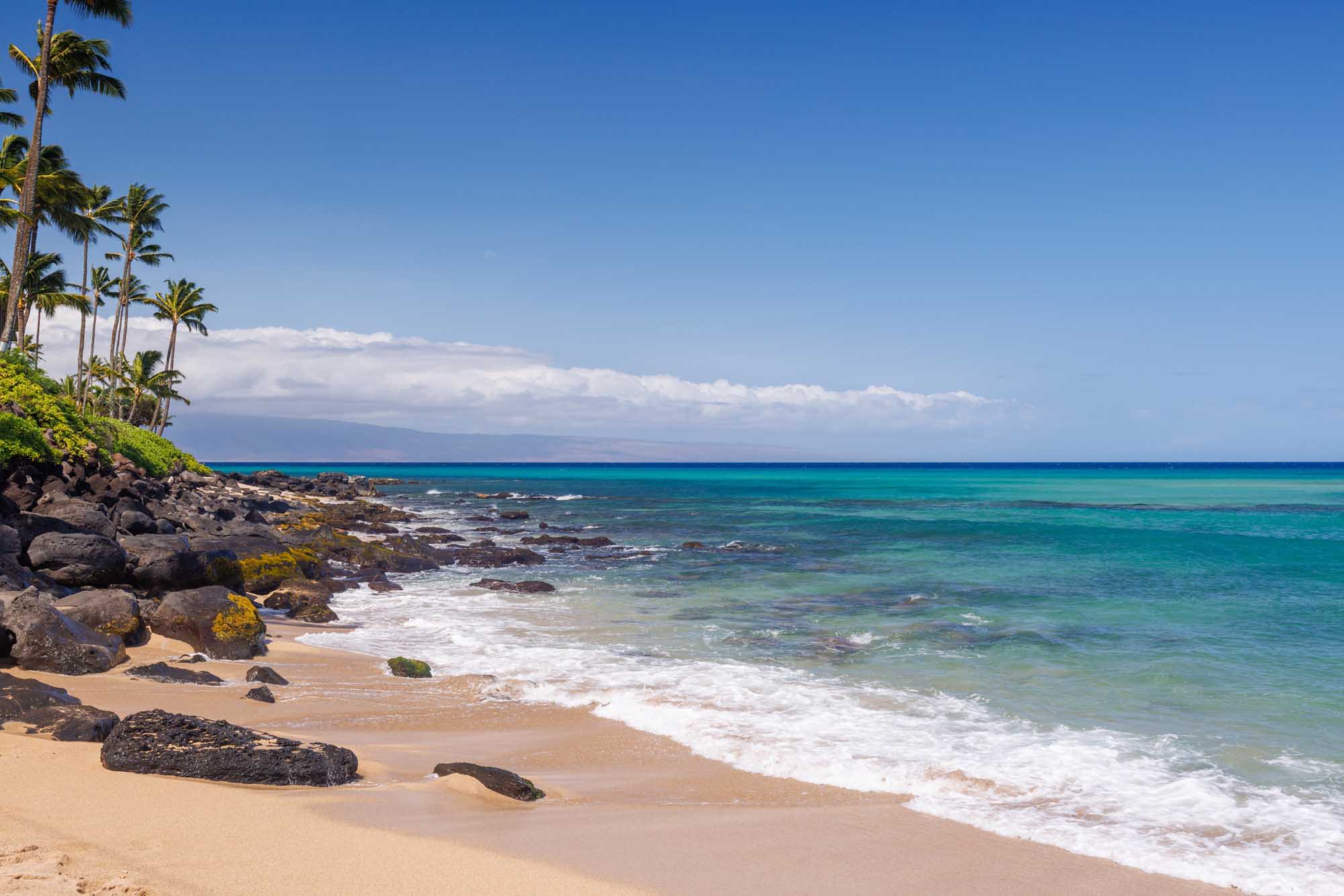 A scenic tropical beach on Maui, Hawaii featuring pristine golden sand, crystal-clear turquoise