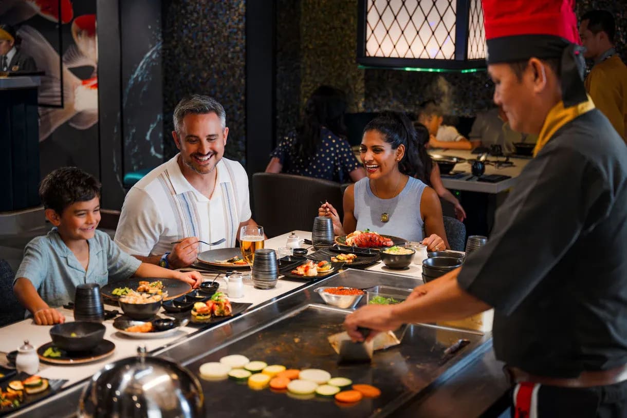 A family of four enjoys an interactive teppanyaki dining experience aboard a Princess Cruises ship