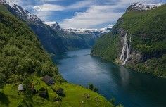 A stunning alpine fjord landscape featuring a pristine turquoise-blue lake surrounded by steep