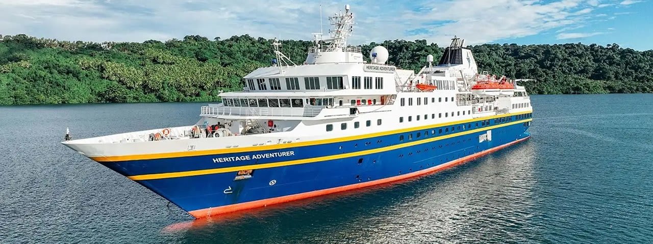 The Heritage Adventurer, a modern expedition cruise vessel, anchors in turquoise tropical waters